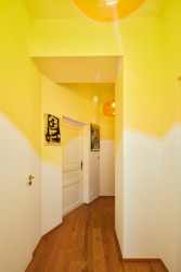 Chodba v patře, prozářená žluto-oranžovou. (Byt na Novém Městě, Helena Ballošová)