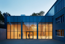 Tělocvična je jednopodlažní a prosklenou stěnou se otevírá k venkovnímu hřišti. (Rozšíření Základní školy Duhovka v Praze, ra15)