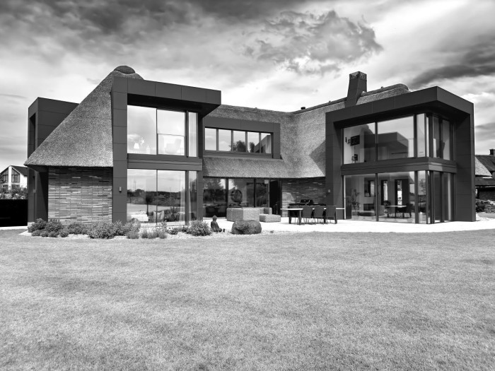 Bezrámové posuvné dveře MB-SKYLINE TYPE R od Aluprof uplatněné v Nemovitost pod doškovou Střechou podél Fjordu Kappeln v Německu.