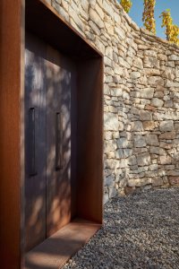 Degustační prostor Fibonacci, Marco Maio Architects: Směrem dolů ze svahu jsou do jedné ze zdí zasazené dveře, který mi se, pokud jsou otevřené, dá prohlédnout k Vltavě.