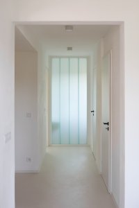 Průhled domem, přes průsvitné stěny vstupuje světlo do středu dispozice (Řadový dům v Čimicích, Plus One Architects)