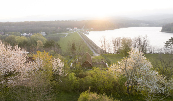 Dům stojí v zeleni přímo nad přehradní hrází. (Víkendový dům nad přehradou, NOIZ architekti)