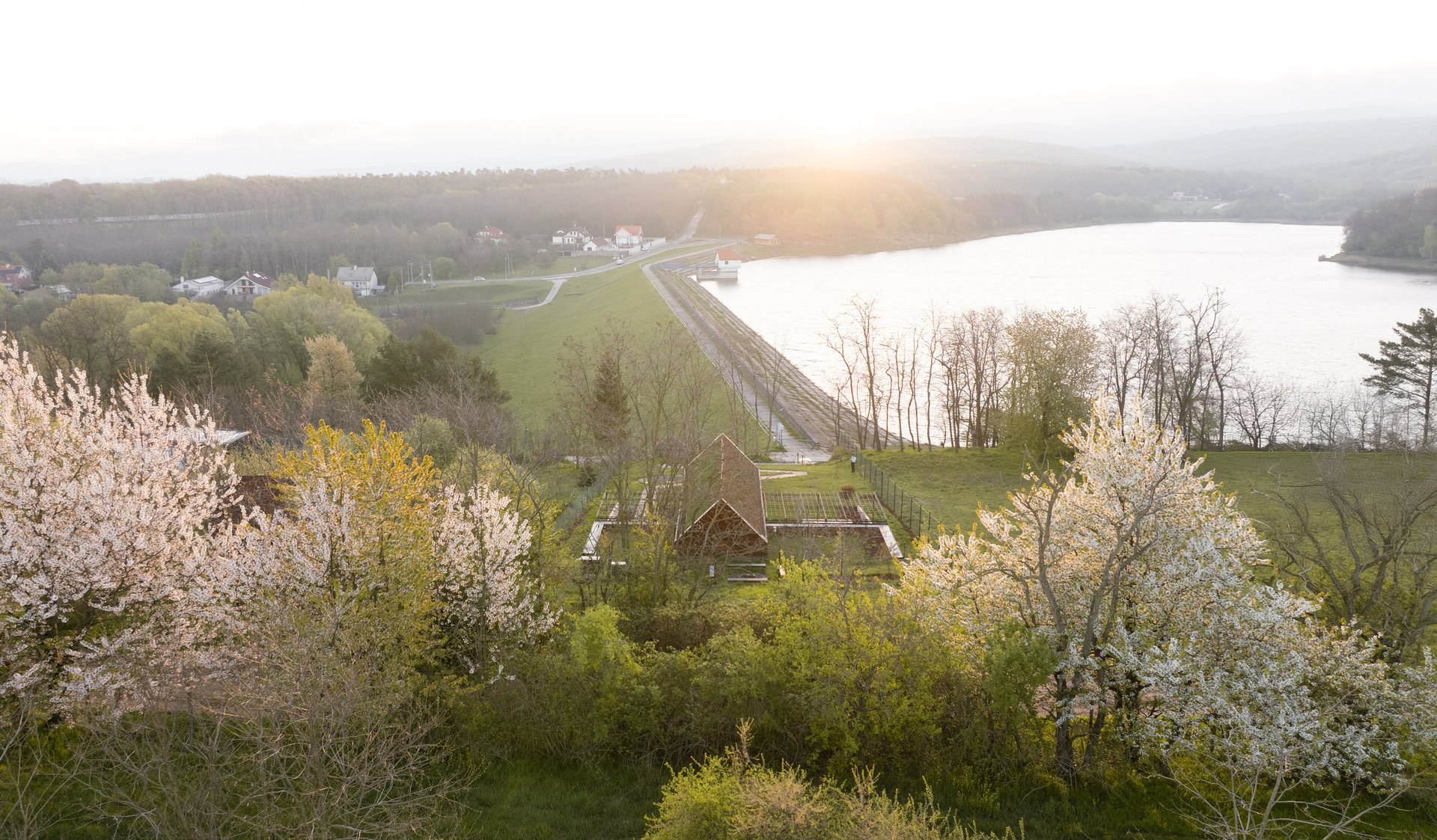 Dům stojí v zeleni přímo nad přehradní hrází. (Víkendový dům nad přehradou, NOIZ architekti)