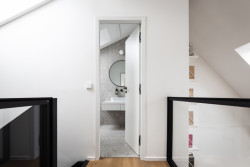 Půdní byt s černým boxem, Komon architekti: Ložnice a koupelna jsou přes otevřený obytný prostor spojené černou lávkou