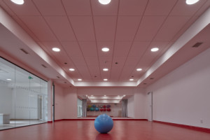 Tělocvičnu zase oživuje červená podlaha. (Dětská léčebna se speleoterapií v Ostrově u Macochy; Adam Rujbr Architects)