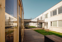 Prostory školní budovy už nestačily, a tak si gymnázium vybudovalo nové třídy přímo na své zahradě. (Venkovní učebny GEVO na Jižním Městě, Ateliér HRA) 