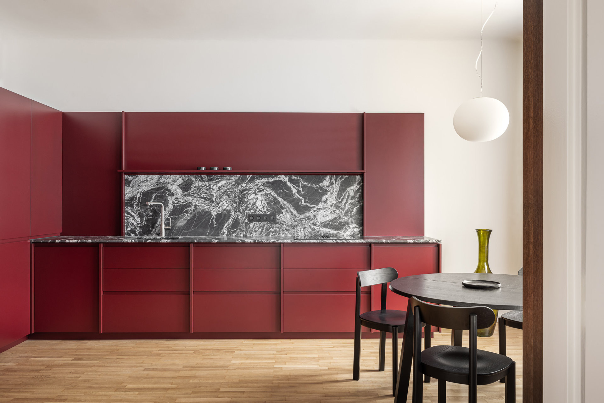 Ústředním prvkem interiéru je vínově laděná kuchyňská sestava s výraznou kamennou kresbou. (Byt Mariánska v Bratislavě, NOIZ architekti)