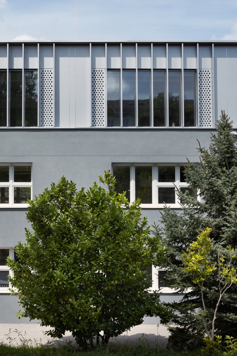 Architekti navrhli nástavbu obléknout do plechu, za ním je ale dřevěná konstrukce. (Rozšíření Základní školy Duhovka v Praze, ra15)
