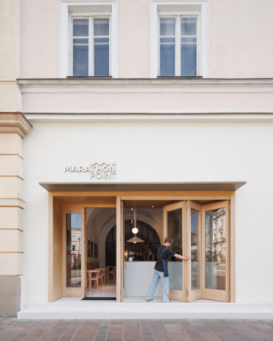 „Otevření do veřejného prostoru hraje ústřední roli,“ popisuje architekt klíčový princip, podpořený skládacími vstupními dveřmi ústícími na hlavní korzo. Prostor tematicky leží přímo na původní trase v centru města a odkazuje na občerstvovací stanice. 