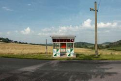 Zelené lesy a béžová pole pod modrou oblohou. Tutéž barevnost dali architetki zastávce. (Zastávka v Podmoklech nad Berounkou, Debyt architektura)