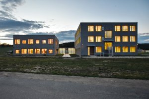 Škola a školka v Letech, Architekt Ondřej Tuček: Šedivé fasády pak ozvláštňují barevné okenní rámy a žaluzie – na školce červené, na škole žluté.