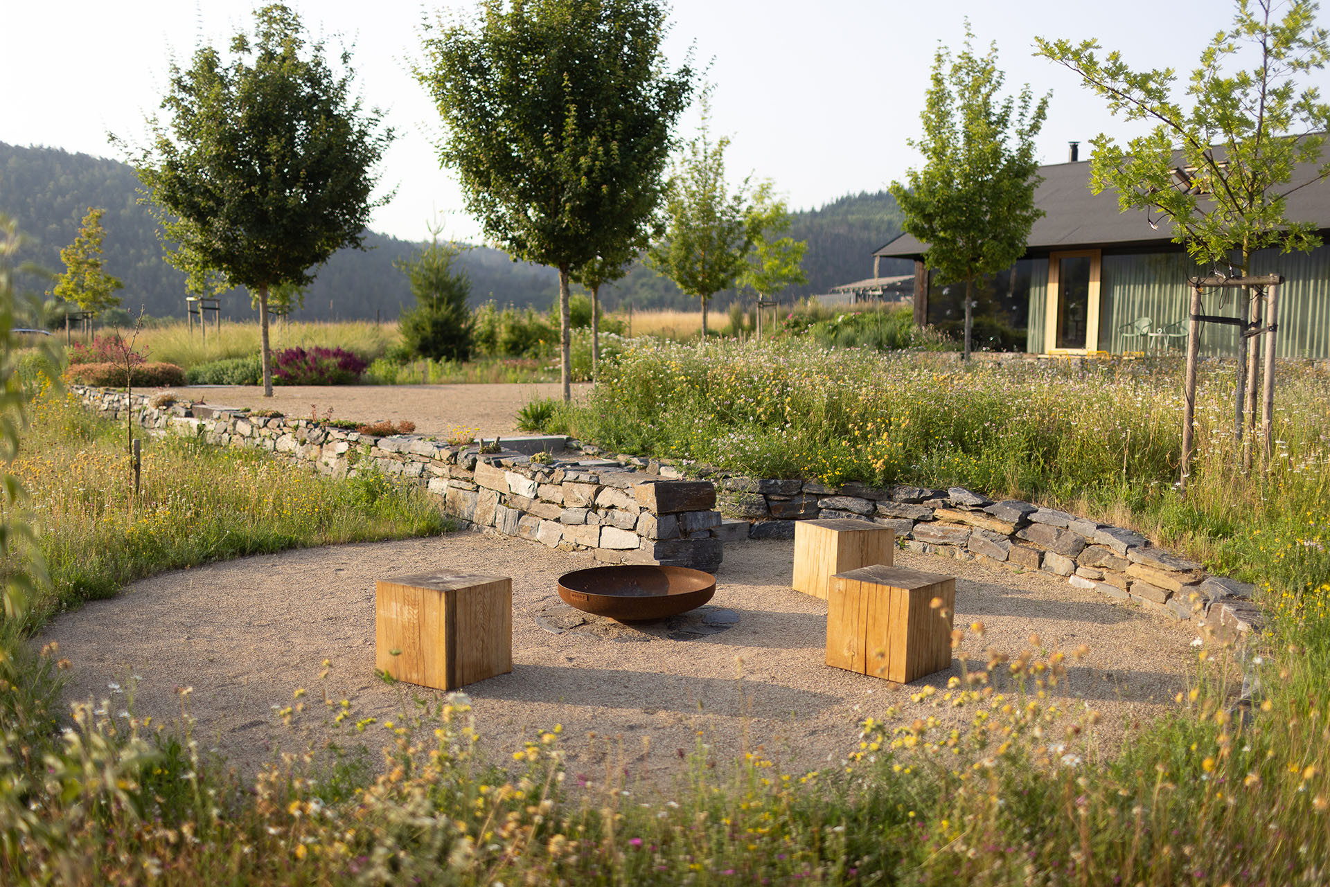 Její součástí je ale taky řada komponovaných částí - zde na fotografii posezení u ohniště. (Zahrada rodinného domu u vodní nádrže Kamýk, Atelier Flera)