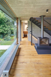 Celoplošně prosklená zeď v obývacím pokoji rámuje výhled do okolní zeleně. (Chata v Posázaví, Studio Sporadical)