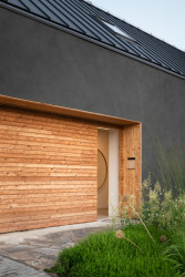Rodinný dům v Polánce, CL3: Na fasádu kombinující černou stěrkovou omítku s dřevěným obložením navazuje černá falcovaná krytina