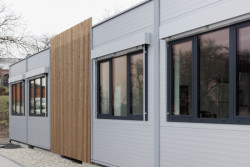 Moderní vzhled dodává stavbě použití elegantních šedých PUR panelů, velkých hliníkových oken a venkovních žaluzií. (ZŠ Drahanovice od společnosti KOMA)