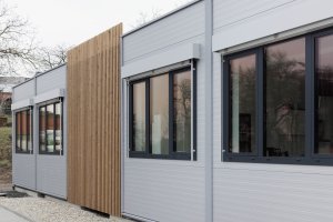 Moderní vzhled dodává stavbě použití elegantních šedých PUR panelů, velkých hliníkových oken a venkovních žaluzií. (ZŠ Drahanovice od společnosti KOMA)
