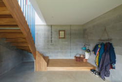 Betonová „noha“ v přízemním patře slouží jako vstupní hala se schodištěm a šatnou. (Rodinný dům v Řevnicích, 0,5 studio)