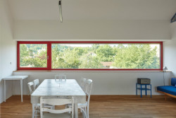 Jižní fasáda je prosklená dlouhým pásovým oknem, které poskytuje výhled do zahrady a okolí. (Rodinný dům v Řevnicích, 0,5 studio)