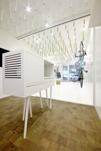 Cyklobutik L27, P6PA+Architects: Špalíková dlažba ošetřená voskem kontrastuje s bílou podlahou v přední části