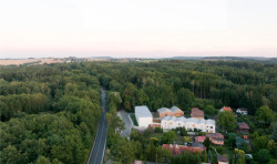 Pozemek se nachází v blízkosti frekventované silnice. Je zasazený v zástavbě malých domů a z jedné strany krytý lesem. (Domov pro seniory s mateřskou školou v Horních Jirčanech, ti architekti)