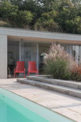 Jednoduché a střídmé materiálové řešení ovšem „rozbíjí“ výrazný odstín červené barvy vybraného nábytku. (Zahradní domek, Adam Lukačovič)