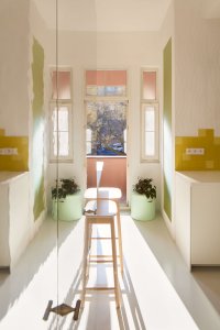 Z barových stoliček se současně otevírá pohled ven vysokými balkonovými dveřmi. (Byt pro malířku v Praze-Holešovicích od Plus One Architects)