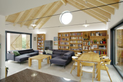 Rodinný dům na Hané, No-A Architekti: Otevřený krov s dřevěným nábytkem a knihovnou z masivu vytváří útulnou atmosféru bez nutnosti výraznějších a extravagantních prvků a doplňků