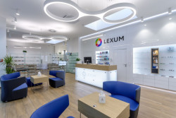 Bílá barva a sklo byly doplněny přírodním dekorem dřeva. Optika CORNEA LEXUM v Praze.