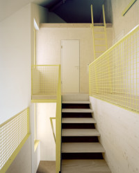 Dům ve svahu, AMUNT Nagel Theissen: Schodiště, které se nachází na střetu geometrií dvou čtverců, vedenpřes otevřenou galerii do dalších pater s ložnicemi a spací půdou