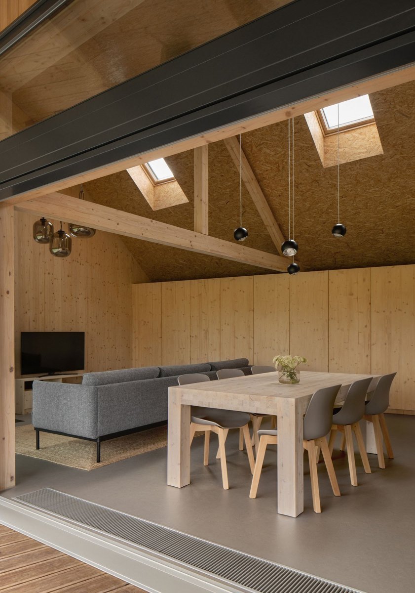 Uvnitř je obývací pokoj s kuchyní a jídelním stolem. (Víkendový dům v Českém ráji, NEW HOW Architekti)