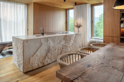 Monotónnost dřevěného interiéru rozbíjí hned několik výrazných prvků. Především je to kamenná kuchyňská linka. (OK PLAN ARCHITECTS, Rodinná bouda)