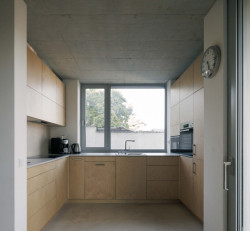 Celá kuchyň je obložená světlým dřevem. (Rodinný dům v Radotíně, Papundekl architekti)