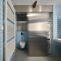 V koupelně vznikly dvě niky, jež odděluje stoupací potrubí. V jedné z nich se nachází wc a ve druhé pračka se sušičkou. Tyto prostory je možné zavřít posuvnou příčkou. (Rekonstrukce bytu ve Vršovicích, Amulet architekti)