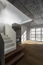 Výrazným prvkem obývací části jsou kamna s šedo-zeleným obkladem a speciální okna s industriálním profilem ve stylu starých továren. (Chata JARO u Prahy, edit! architects)