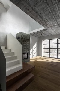 Výrazným prvkem obývací části jsou kamna s šedo-zeleným obkladem a speciální okna s industriálním profilem ve stylu starých továren. (Chata JARO u Prahy, edit! architects)