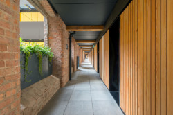 Byty jsou propojeny vnějšími pavlačemi. (Projekt Crusader Works: Přádelny v centru Manchesteru přestavěné na bydlení, studio shedkm)