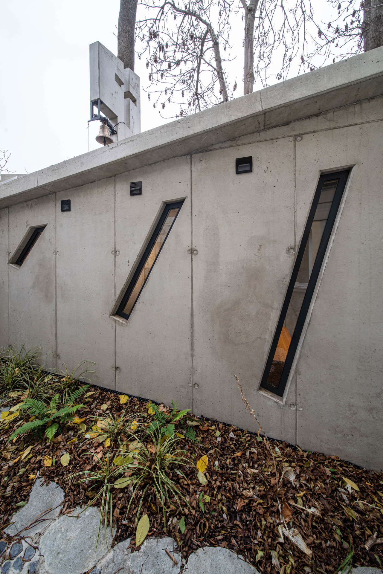 Boční strana kaple je protkaná šikmými podlouhlými okny. (Kaple v Praze-Záběhlicích; JIRSA – ARCHITEKTI)