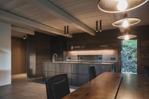 Interiér pracuje s tmavým dřevem, přiznanými trámy a klidnou atmosférou. (Chalupa ve stráni; Mimosa Architekti)