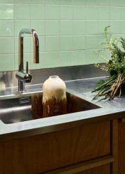 Kuchyňská linka je zhotovena z nerezového plechu, který se objevuje i na nábytku v koupelně či předsíni. (Rekonstrukce bytu ve Vršovicích, Amulet architekti)