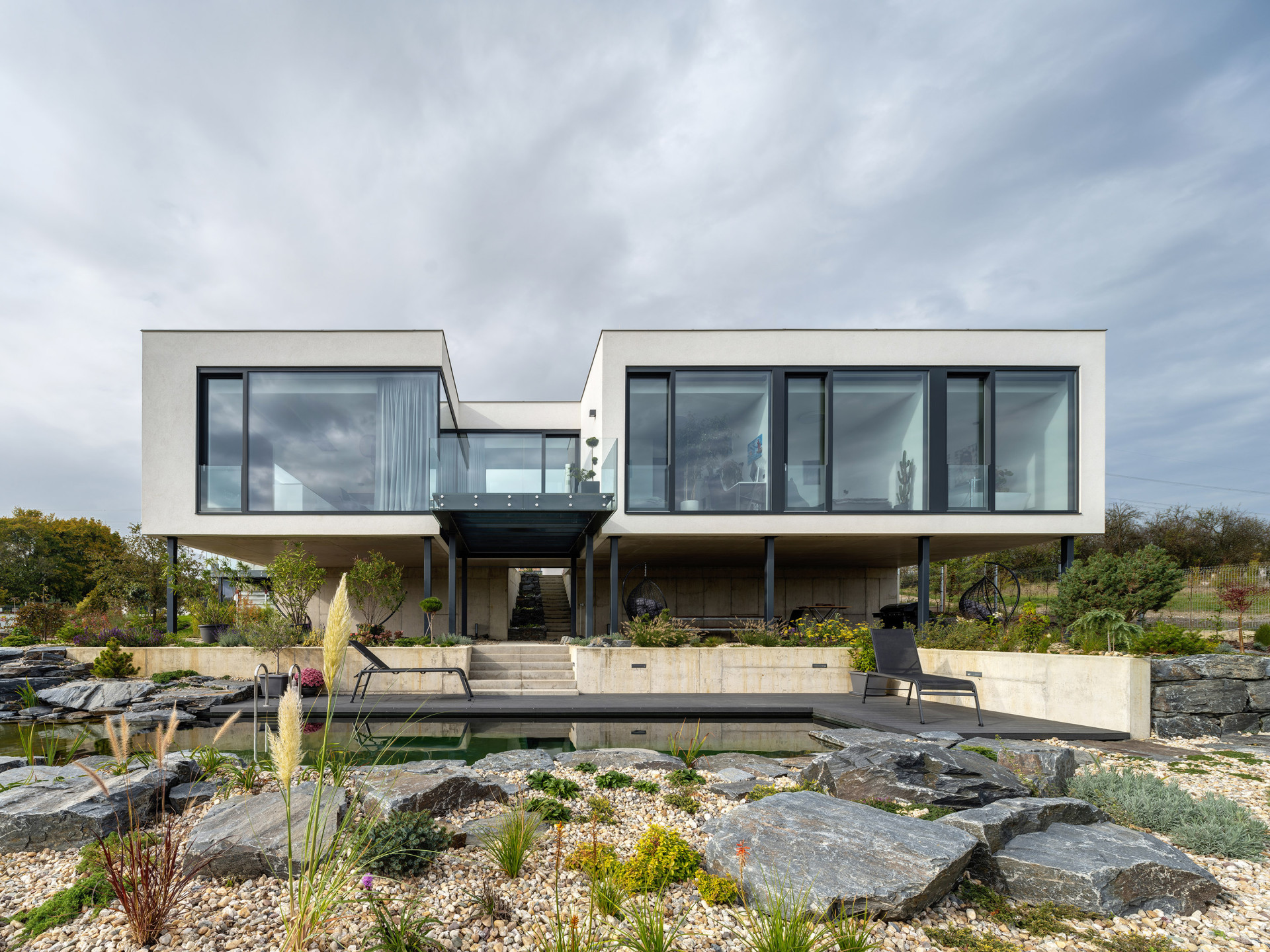 Hlavní obytný trakt vily je vysunutý nad terén a podpírají ho štíhlé ocelové sloupy. (Vila u Prahy, boq architekti)