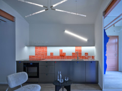 Je vybaven nerezovou kuchyní s červeno-růžovými glazovanými obklady nizozemské značky Palet. (Rekonstrukce pavlačového domu v Praze-Nuslích, Plus One Architects) 