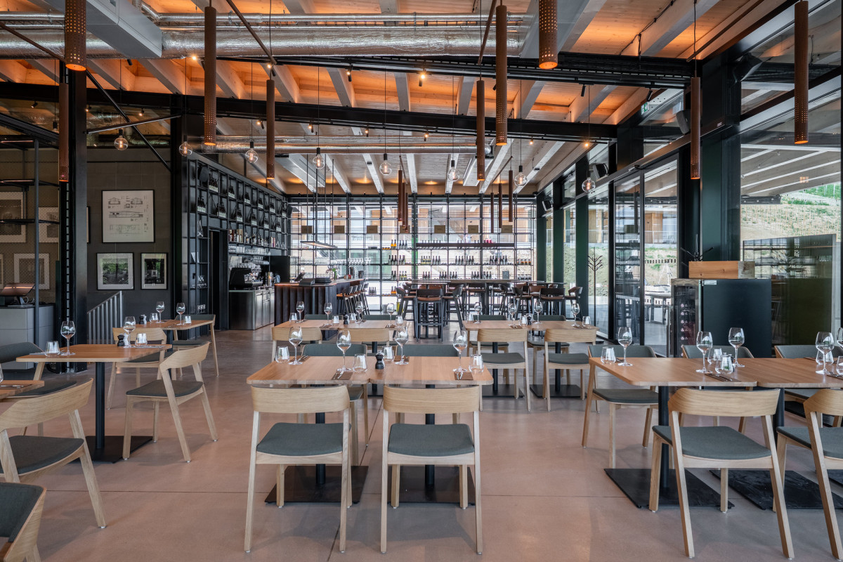 Interiéru restaurace dominují tlumené barvy, výraznější akcent dodává černá, která je i na nosné konstrukci. (ARTEVINI Resort & Winery u Velkých Pavlovic; znamení čtyř – architekti)