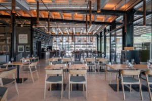 Interiéru restaurace dominují tlumené barvy, výraznější akcent dodává černá, která je i na nosné konstrukci. (ARTEVINI Resort & Winery u Velkých Pavlovic; znamení čtyř – architekti)
