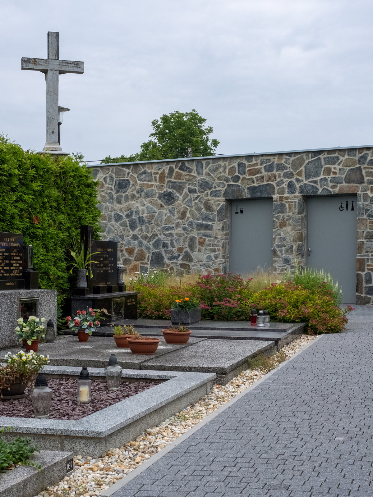 Vstup lemují střídmé světle šedé dveře s decentním piktogramem. (Zázemí hřbitova; bydloarchitekti)