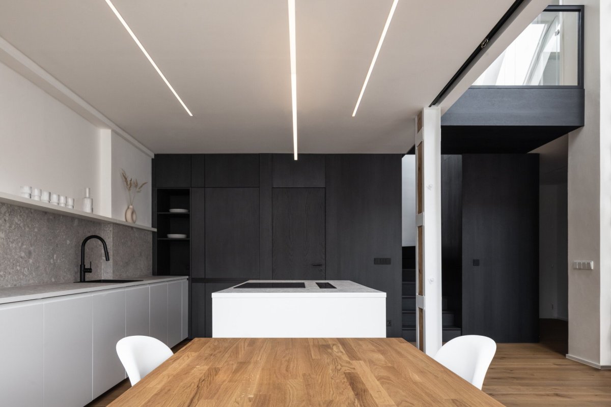 Půdní byt s černým boxem, Komon architekti: Černá olejovaná dýha boxu v obležení bílých stěn a nábytku zřetelně vystupuje a svým minimalistickým zpracováním a absencí detailu nutí pozorovatele zaměřit se na její čisté linie a jasnou texturu dřeva