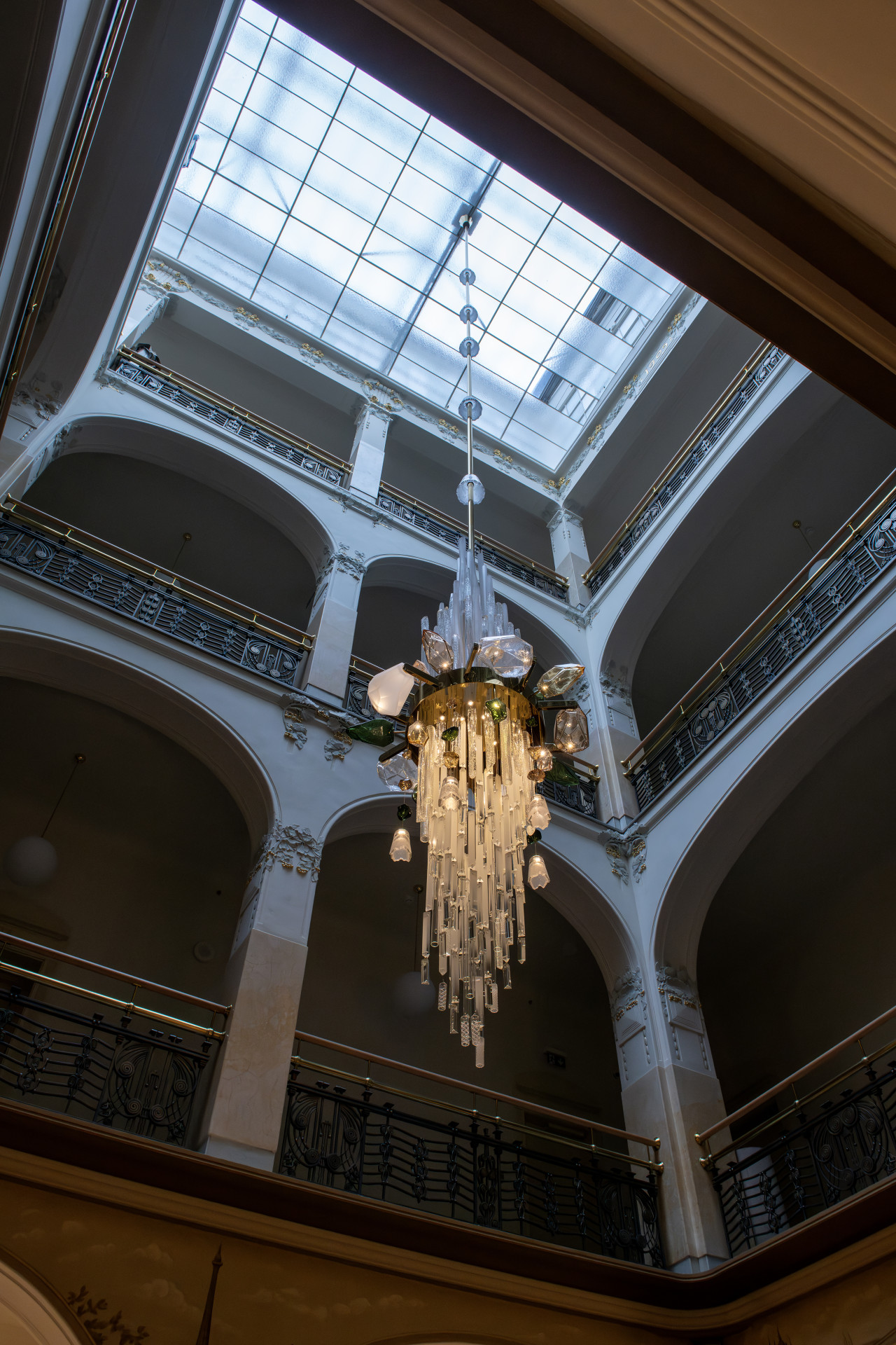 Uprostřed dvorany v historické části hotelu zase visí rozměrný (a pořádně těžký) lustr, v němž je otisknut příběh o hledání elixíru věčného mládí z doby Rudolfa II. Navrhla ho architektka Pavla Doležalová z Chapman Taylor a podle jejích slov má zhmotňovat „národní poklad, kterým je pro Česko sklářský průmysl“.