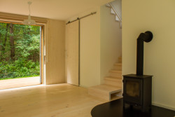 System Recovery Architects - Domek mezi lesy: Díky velkým oknům je uvnitř velké množství denního světla