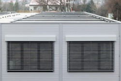 Moderní vzhled dodává stavbě použití elegantních šedých PUR panelů, velkých hliníkových oken a venkovních žaluzií. (ZŠ Drahanovice od společnosti KOMA)