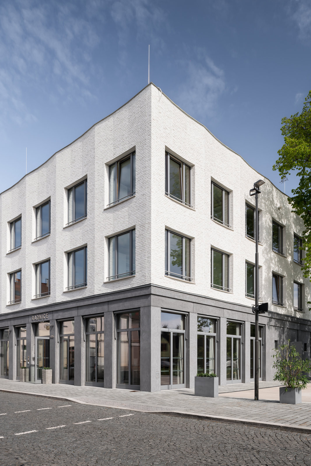 Detail vztahu budovy k náměstí - objekt působí jako přirozený organizující prvek veřejného prostoru. (Nová radnice s plastickou fasádou; re:architekti)