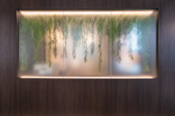 Do jedné je zasazeno velké prosklení s vloženými květinami, kterým proniká přirozené světlo.